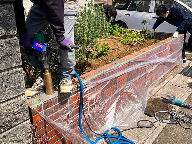 レンガ花壇の上で職人が基礎工事を行う様子