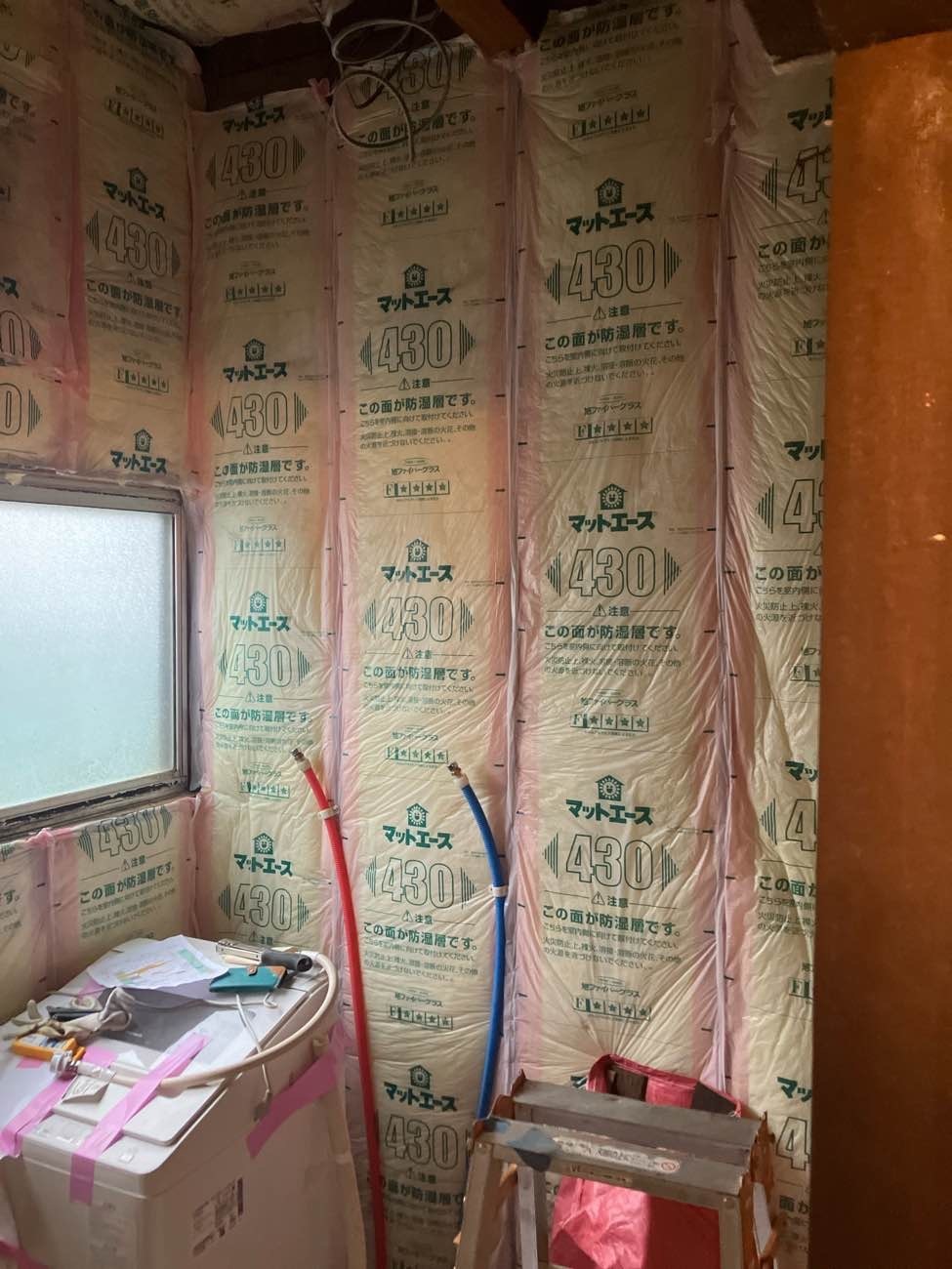 柏市I様邸の水廻りリフォーム施工中。洗面室の壁の柱と柱のあいだに充填したグラスウール断熱材