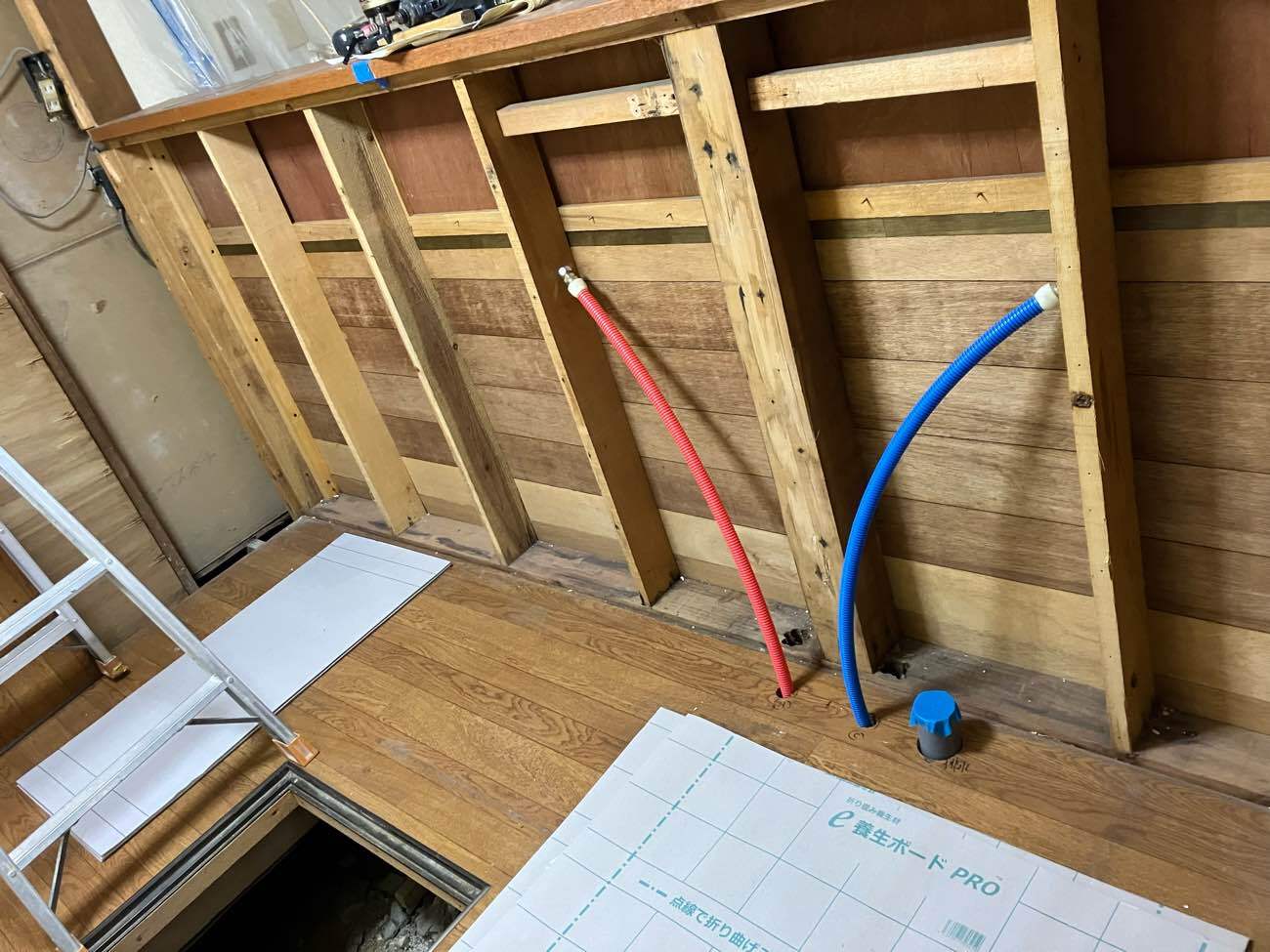 柏市I様邸の水廻りリフォーム施工中。解体した壁の内部に新しく引き直した給湯管（赤）と給水管（青）の樹脂配管