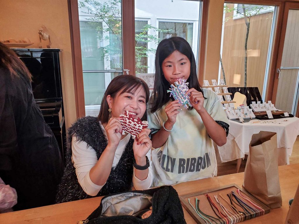 完成したマクラメ作品を持って笑顔を見せる参加者