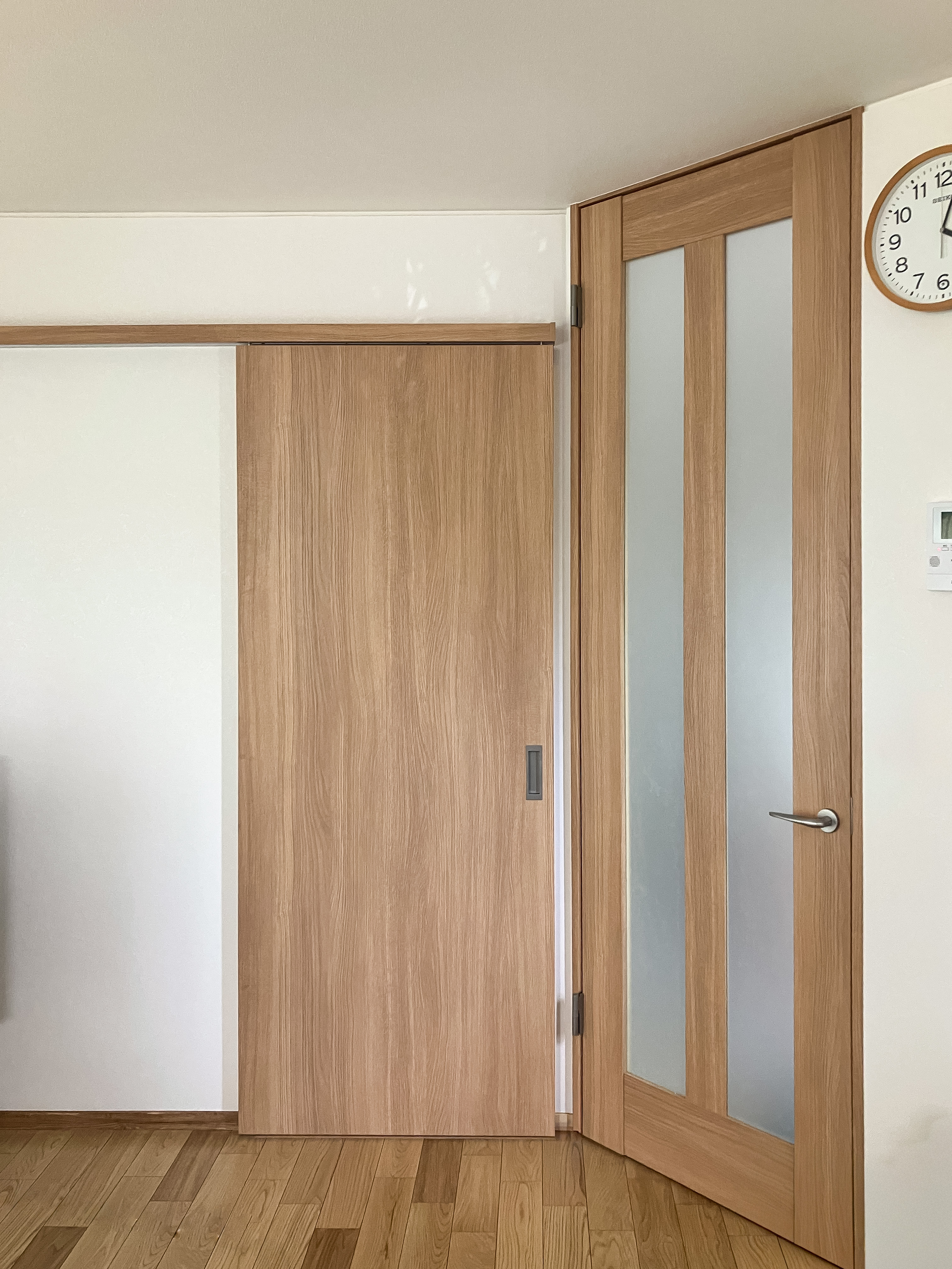 柏市の内部リフォームで交換した室内建具。木目の引き戸とガラス入りドアにそろえ、明るく軽やかな印象になった室内