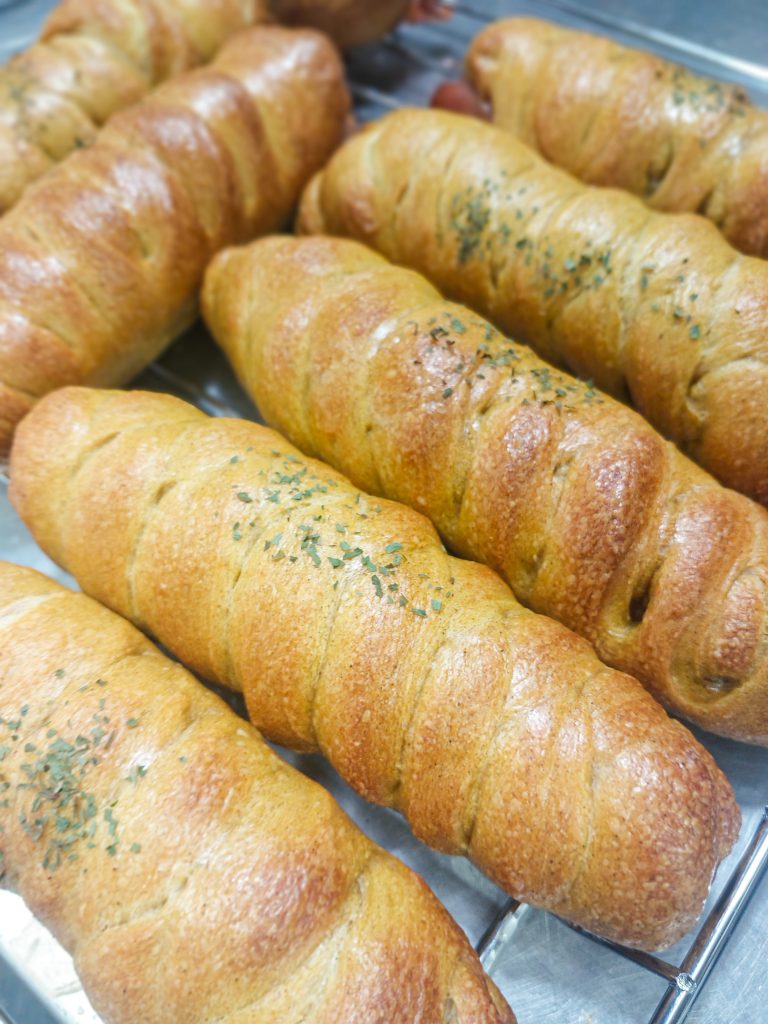 こまいぬベーグル堂の焼き立てハーブロールパン。ハーブが練り込まれたこんがりキツネ色のロールパンがトレーに並ぶ