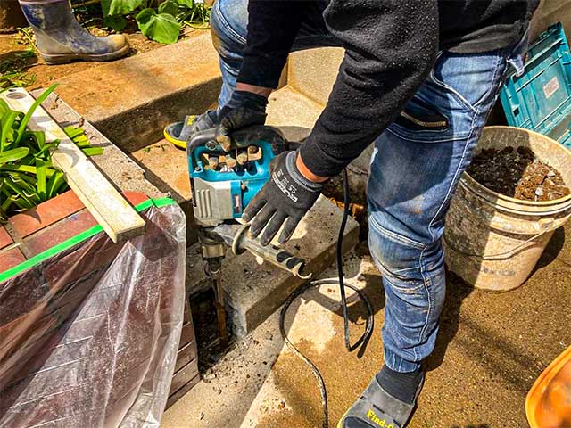 職人が工具を使って新しいフェンス基礎を施工している様子