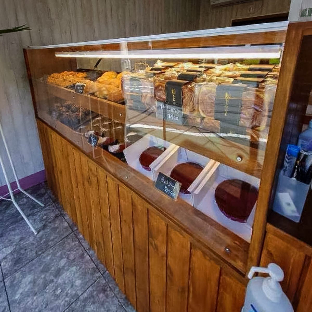 松戸市メロンLAB上本郷駅前店の開店後。木製ショーケースの全景、アクリル板越しにパンとお菓子が並ぶ